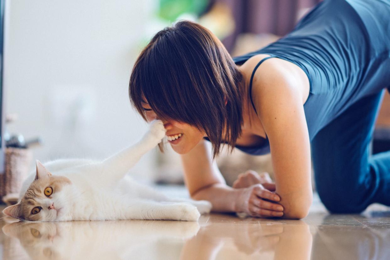 woman on the floor with cat, cat's paw touching her nose