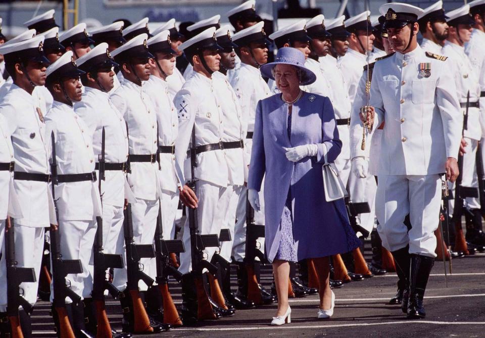 <p>The queen wore a purple dress, tonal coat and wide-brimmed hat, white heels, and a pair of white gloves for a royal visit to Cape Town, South Africa.</p>