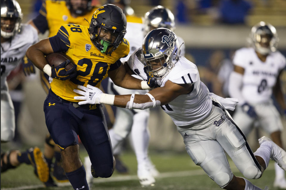 California running back Damien Moore (28) fends off Nevada linebacker Daiyan Henley (11) during the first quarter of an NCAA college football game Saturday, Sept. 4, 2021, in Berkeley, Calif. (AP Photo/D. Ross Cameron)