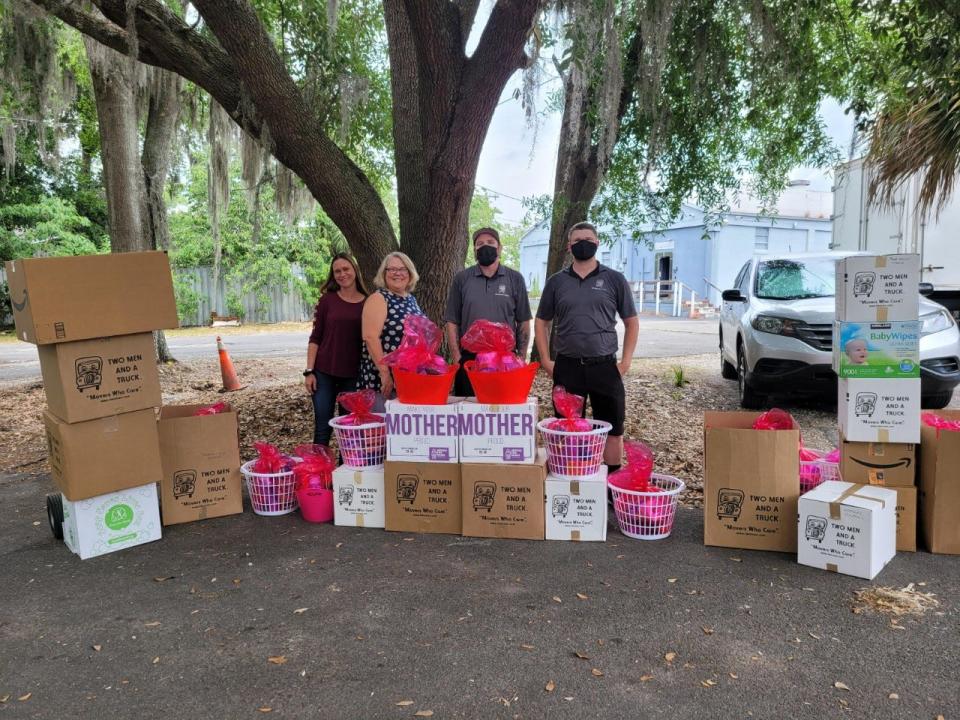 Ray and Vincent from the Two Men and a Truck moving company pose in front of some of the goods donated to the Ocala Domestic Violence/Sexual Assault Center.