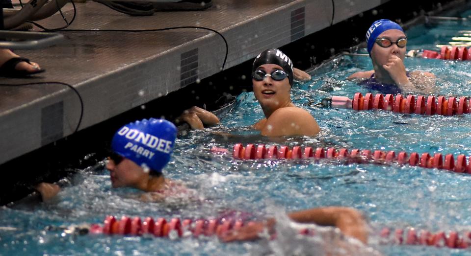 Annabelle Williams of Milan (center) looks up at the clock after winning the 100-yard freestyle, behind in second Emma O'Connell of Dundee and third in foreground Lia Parry in the Monroe County Swim Finals Saturday.