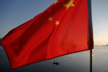 North Korean fishermen are seen as a Chinese flag flutters from the Broken Bridge as the sun sets over the Yalu River between the North Korean town of Sinuiju and Dandong in Liaoning Province, China, November 19, 2017. REUTERS/Damir Sagolj/Files