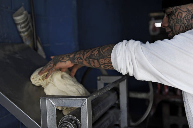 Felix, of the Barrio 18 gang, prepares dough at a bakery they operate in Ilopango, El Salvador on January 21, 2012. With tattoos all the way up to his face, Felix is working to give a good life to his two daughters, who are four and two years old