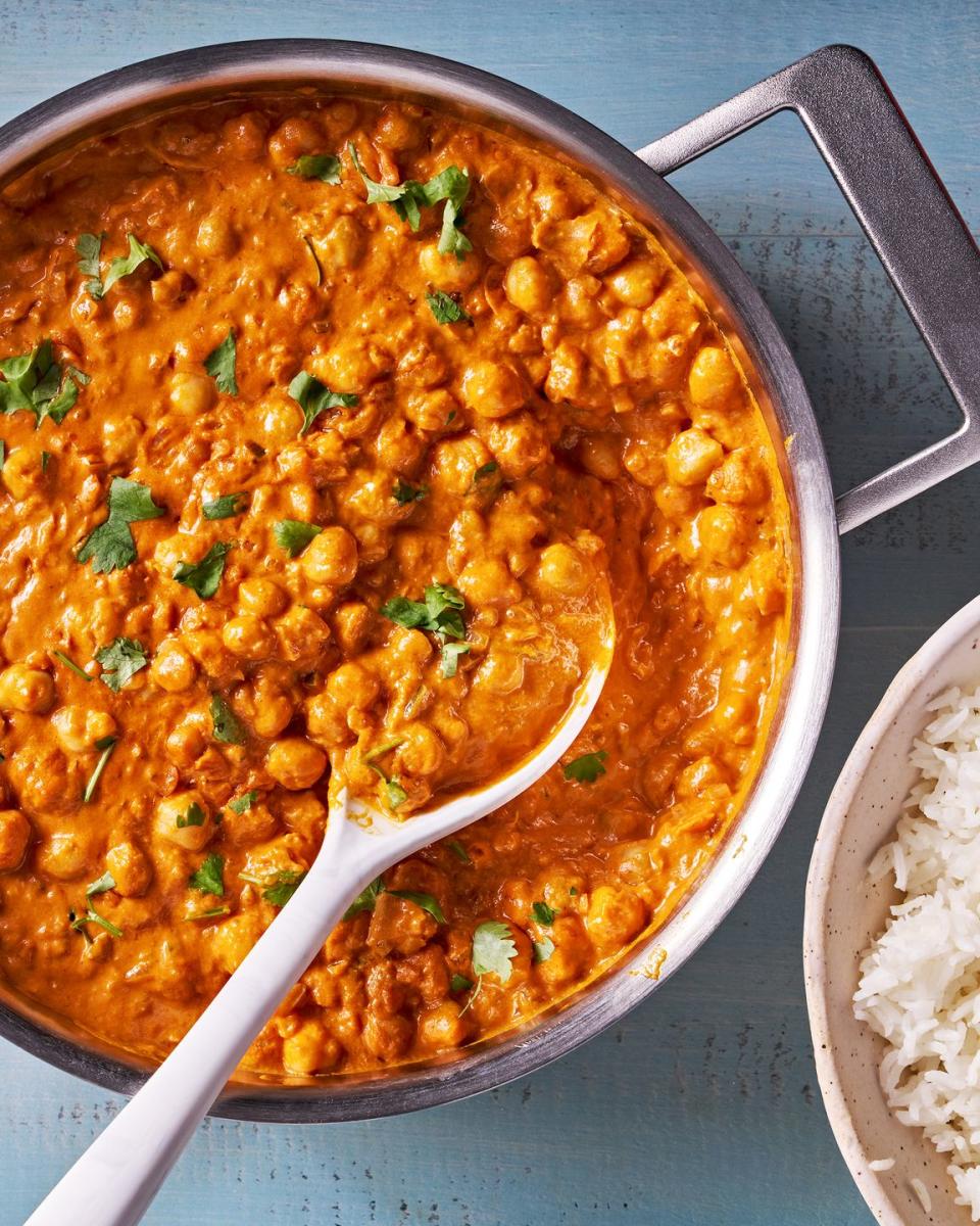 indian butter chickpeas in a pan with a bowl of rice on the side