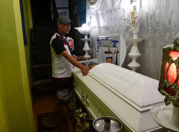 Saldy Delos Santos, father of the 17 year-old student Kian Loyd stands next to the coffin of his son