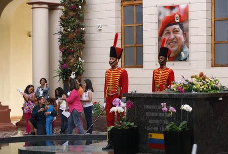 Children read their stories, next to the tomb of late Venezuelan President Hugo Chavez, during a writing workshop at the 4F military fort in Caracas December 14, 2014. REUTERS/Carlos Garcia Rawlins