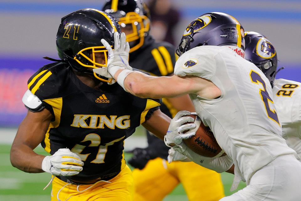 DeWitt's Nicholas Fiegler (2) stiff arms Detroit King's Terrence Brown during a run in the Michigan High School Athletic Association Division 3 final at Ford Field in Detroit on Saturday, Nov. 27, 2021. King won, 25-21.