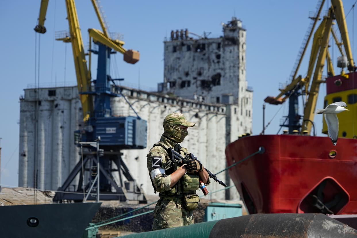 FILE - A Russian soldier guards a pier with the grain storage in the background at an area of the Mariupol Sea Port which has recently started its work after heavy fighting in Mariupol, on the territory which is under the Government of the Donetsk People's Republic control, eastern Ukraine, Sunday, June 12, 2022. Despite getting bogged down in Ukraine, the Kremlin has resisted announcing a full-blown mobilization, a move that could prove to be very unpopular for President Vladimir Putin. That has led instead to a covert recruitment effort that includes trying to get prisoners to make up for the manpower shortage. This photo was taken during a trip organized by the Russian Ministry of Defense. (AP Photo, File)