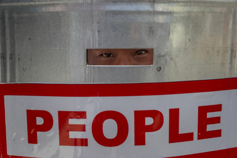 An anti-coup protester watch through a shield after police blocked their march in Mandalay, Myanmar, Wednesday, Feb. 24, 2021. Protesters against the military's seizure of power in Myanmar were back on the streets of cities and towns on Wednesday, days after a general strike shuttered shops and brought huge numbers out to demonstrate. (AP Photo)