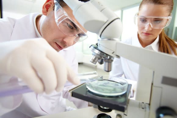 Two clinical researchers at work using a microscope.