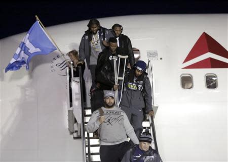 Seattle Seahawks' Richard Sherman (R) carries his crutches as he exits the team's chartered flight home after winning NFL Super Bowl XLVIII at Seatac Airport in Seattle, Washington February 3, 2014. REUTERS/Jason Redmond