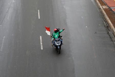 Motorcycle taxi drivers working for online ride-hailing start-ups ride on their way to a protest against low tariffs outside parliament in Jakarta, Indonesia, April 23, 2018. REUTERS/Darren Whiteside