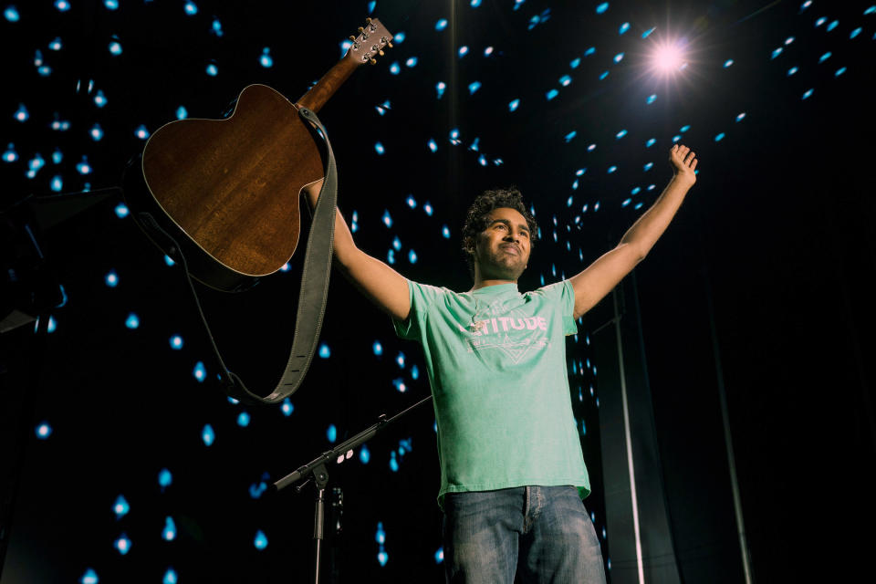 man holding up a guitar on stage