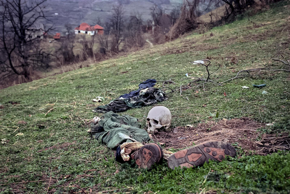 FILE- In this Tuesday, April 2, 1996, file photo, the remains of two bodies and pieces of clothing lie in a field at a suspected mass grave site in the village of Konjevic Polje, approximately 20km (12 miles), north west of Srebrenica. Survivors of the genocide in the eastern Bosnian town of Srebrenica, mainly women, will on Saturday July 11, 2020, commemorate the 25th anniversary of the slaughter of their fathers and brothers, husbands and sons. At least 8,000 mostly Muslim men and boys were chased through woods in and around Srebrenica by Serb troops in what is considered the worst carnage of civilians in Europe since World War II. The slaughter was also the only atrocity of the brutal war that has been confirmed an act of genocide.(AP Photo/Vadim Ghirda, File)