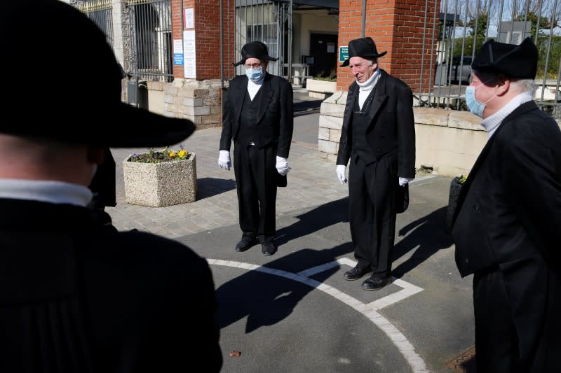 Members of the Charitable Brotherhood which first formed during the plague 800 years ago, talk in front of the cemetery after a burial ceremony in Bethune