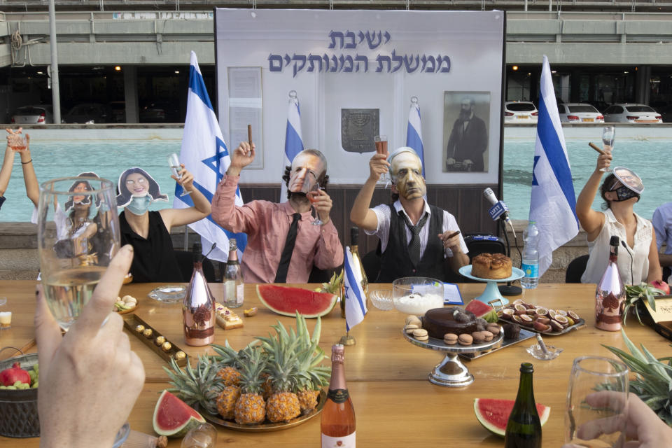 Israeli activists wear masks depicting Israeli Prime Minister Benjamin Netanyahu and other ministers during a mock cabinet meeting protesting the government's response to the health and economic crisis in Tel Aviv, Israel, Sunday, Sept. 6, 2020. Hebrew reads: "Detached government meeting" . (AP Photo/Sebastian Scheiner)