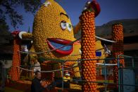 A worker places citrus fruits on a carnival float during the 90th edition of the Lemon Festival in Menton, southern France, Saturday, Feb. 17, 2024. (AP Photo/Daniel Cole)