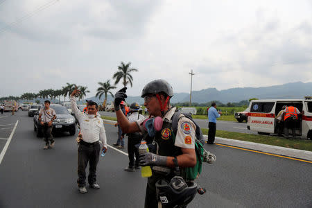 A firefighter gestures on a road near an area affected by the eruption of Fuego volcano in Escuintla, Guatemala June 5, 2018. REUTERS/Luis Echeverria