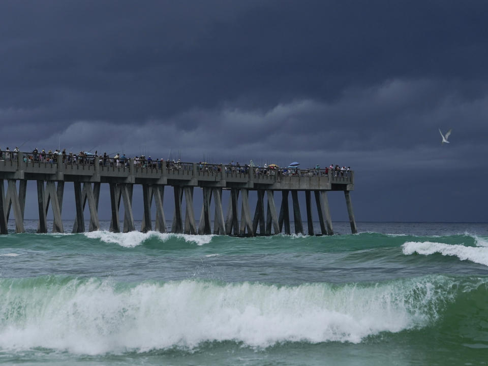 People gather on Navarre Beach Fishing Pier despite storm clouds approach the shore in Navarre Beach, Fla., Sunday, June 16, 2024. (AP Photo/Kiichiro Sato)