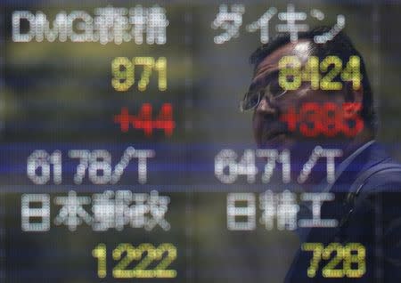 A man is reflected on a stock quotation board outside a brokerage in Tokyo, Japan July 11, 2016. REUTERS/Issei Kato/File Photo