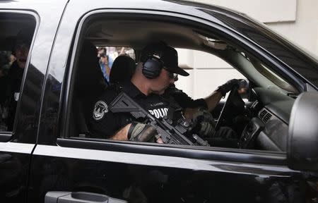 A police officer holds his weapon in a vehicle as they monitor a march by various groups, including "Black Lives Matter" and "Shut Down Trump and the RNC" ahead of the Republican National Convention in Cleveland, Ohio, U.S. July 17, 2016. REUTERS/Shannon Stapleton