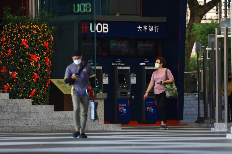 People wearing protective mask walk past an automated teller machine (ATM) at a United Overseas Bank Ltd (UOB) branch in the central business district on February 23, 2021 in Singapore. (Photo by Suhaimi Abdullah/NurPhoto via Getty Images)