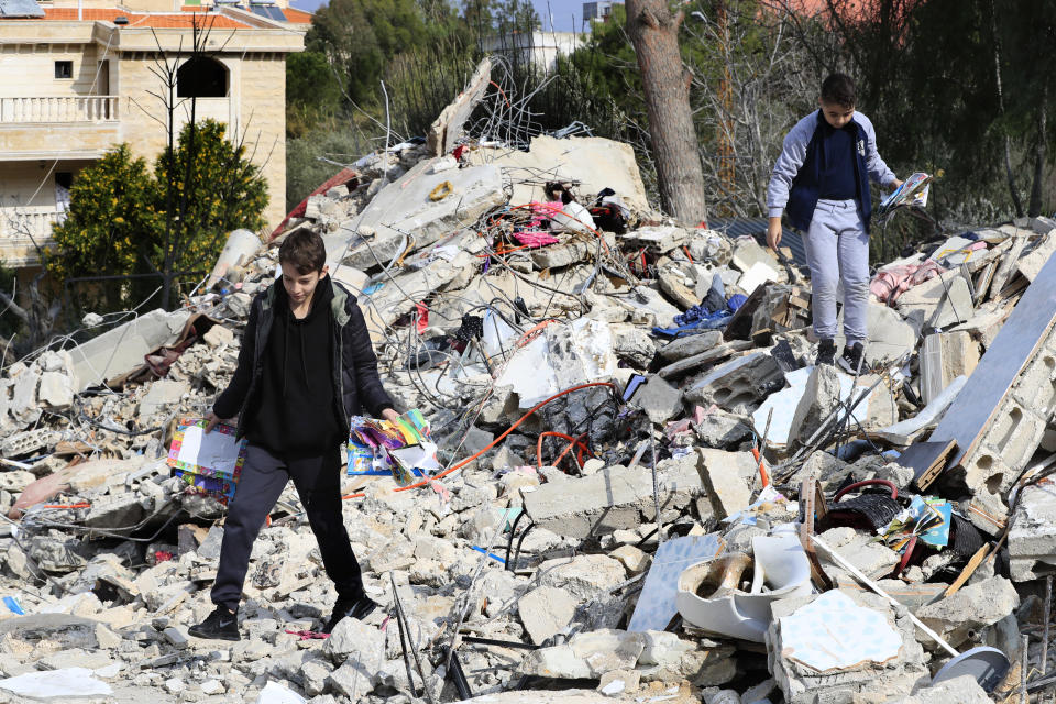 Lebanese boys walk on the rubbles of a house that was destroyed by an Israeli airstrike Tuesday night, in Bint Jbeil, South Lebanon, Wednesday, Dec. 27, 2023. One Hezbollah fighter and two civilians, a newlywed couple, were killed in an overnight Israeli strike on a family-owned residential building in the town of Bint Jbeil, local residents and state media said Wednesday. (AP Photo/Mohammed Zaatari)