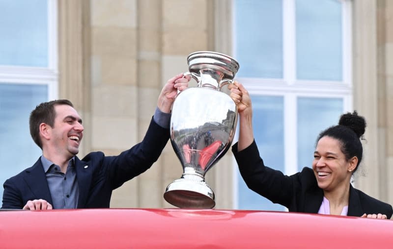 Philipp Lahm (L), Tournament Director of the European Football Championship, holds the trophy for the European Football Championship, which is being held in Germany this year, together with former national soccer player Celia Sasic. The trophy is displayed in the courtyard of honor in front of the new castle. Bernd Weißbrod/dpa