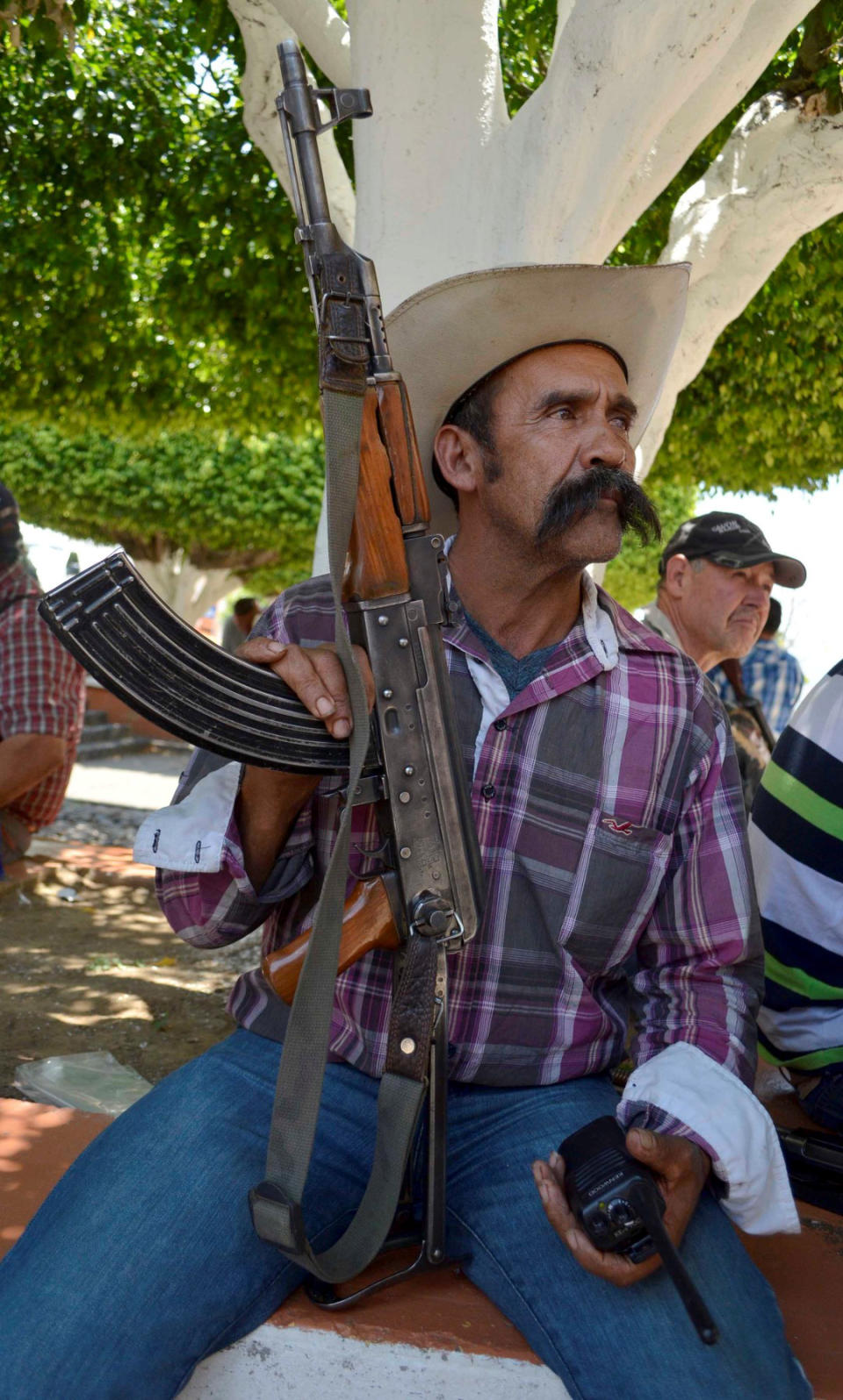 A member of a self-defense group sits with his weapon as he waits during the first day of weapons registration in Coalcoman, Mexico, Monday, 28, 2014. The confusing proliferation of false self-defense groups in Michoacan and instances of alleged looting and killings by legitimate vigilantes have led the federal government to tell the vigilantes they have to demobilize by May 10 but the vigilantes, who usually carry assault rifles that are prohibited for civilian use, only have to turn in their heaviest weapons, such as .50-caliber sniper rifles. They will be allowed to keep, but not publicly carry, AR-15 and AK-47 assault rifles, as long as they register them with the army. (AP Photo/Agencia Esquema)