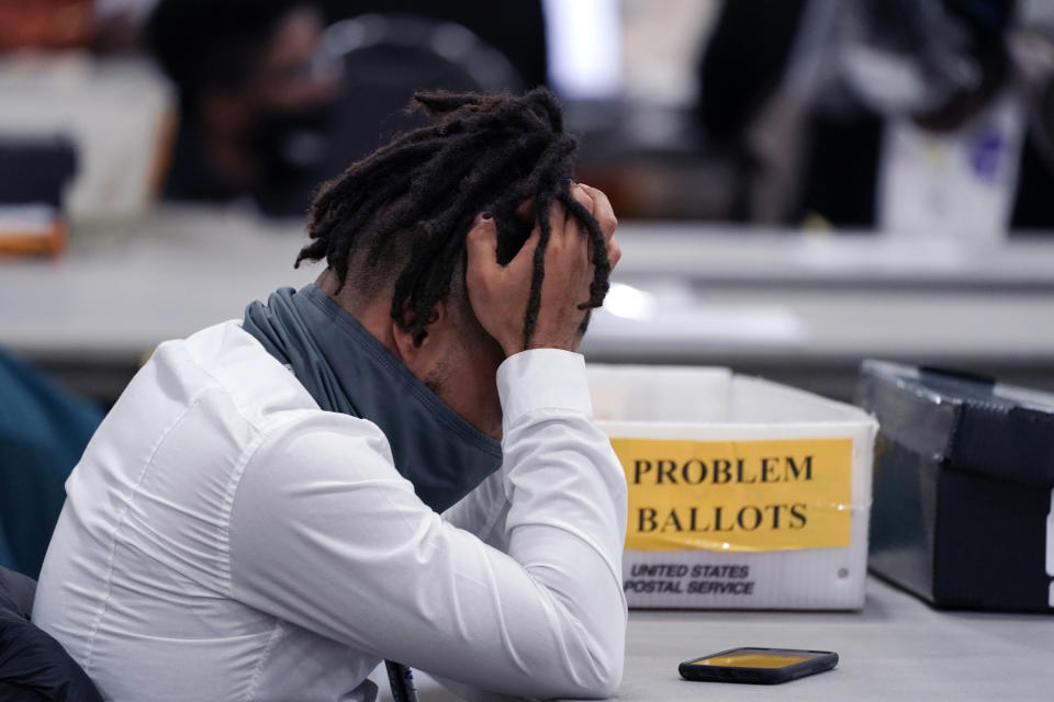 An elections worker rubs his head in the closing hours where absentee ballots were processed at the central counting board, Wednesday, Nov. 4, 2020, in Detroit. (AP Photo/Carlos Osorio)