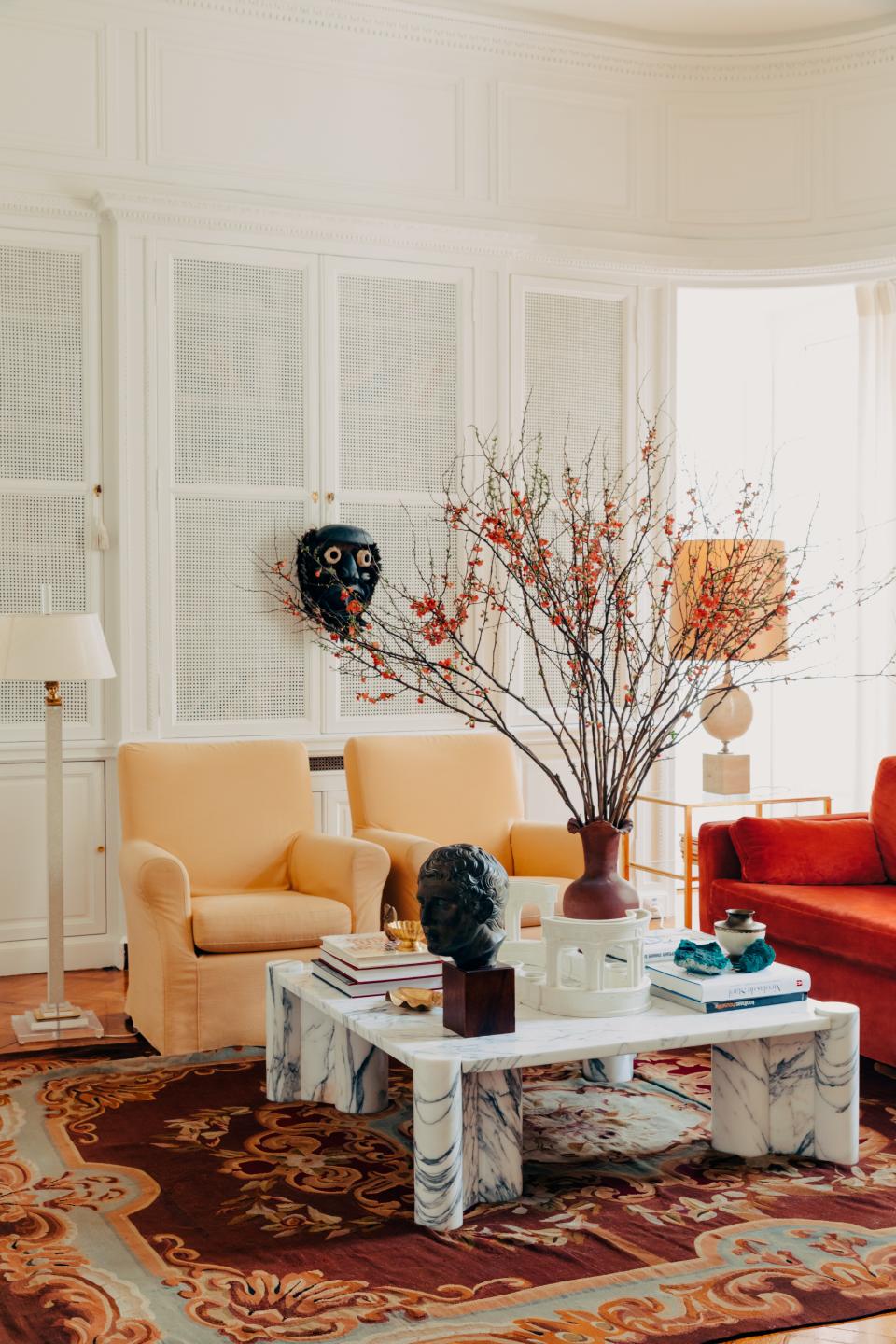 The library features a gale Aulenti Marble cocktail table, a 19th-century French rug, and a pair of David Hicks armchairs covered in a Pierre Frey fabric. Vintage lamps; 20th-century African mask.