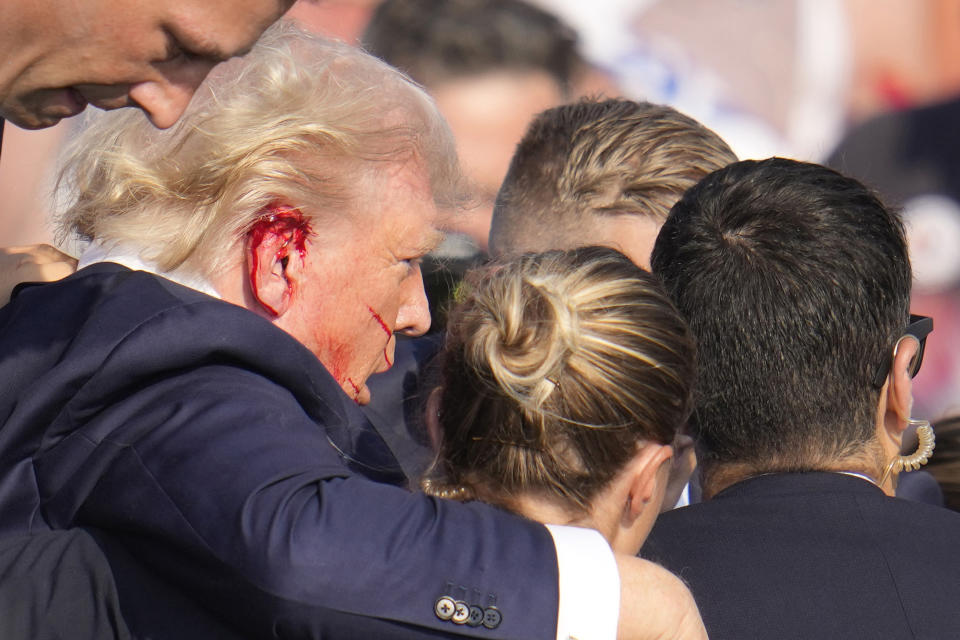 El expresidente y virtual candidato presidencial republicano de Estados Unidos Donald Trump es rodeado por agentes del Servicio Secreto mientras baja del estrado en un mitin de campaña en Butler, Pensilvania, el sábado 13 de julio de 2024. (AP Foto/Gene J. Puskar)