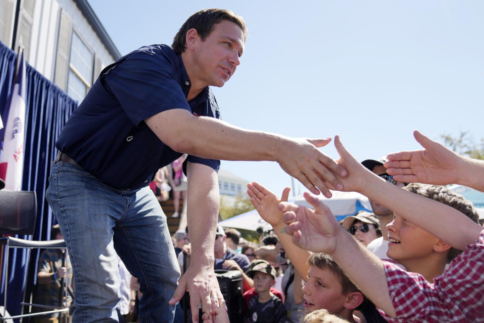 FILE - Republican presidential candidate Florida Gov. Ron DeSantis shakes hands with fairgoers after taking part in a Fair-Side Chat with Iowa Gov. Kim Reynolds at the Iowa State Fair, Saturday, Aug. 12, 2023, in Des Moines, Iowa. Republicans are responding to a late summer spike in COVID-19 by raising familiar fears that government-issued lockdowns and mask mandates are on the horizon. GOP presidential hopefuls including Florida Gov. Ron DeSantis, South Carolina Sen. Tim Scott and former President Donald Trump have spread this narrative. (AP Photo/Jeff Roberson, File)