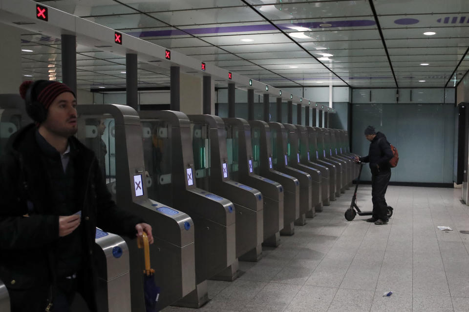 A commuter with a scooter walks next to automatic gates at the Gare Saint Lazare station in Paris, France, Monday, Dec. 16, 2019. French transport strikes against a planned overhaul of the pension system entered their twelfth day Monday as French president Emmanuel Macron's government remains determined to push ahead with its plans. (AP Photo/Francois Mori)