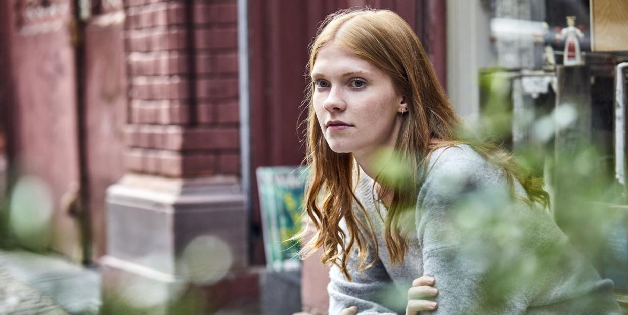 serious young woman sitting at house entrance