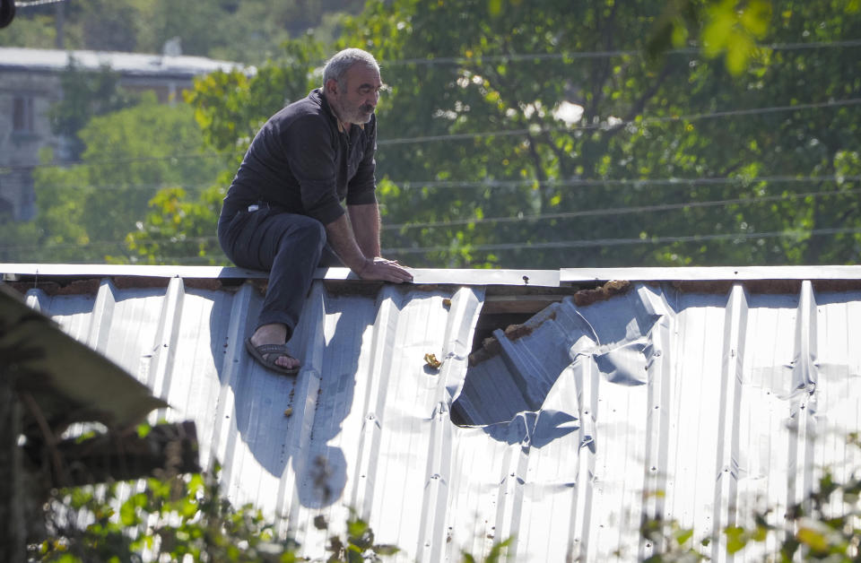 A man examines damage of the roof of his house after shelling by Azerbaijan's artillery, during a military conflict in Stepanakert, the separatist region of Nagorno-Karabakh, Saturday, Oct. 10, 2020. Armenia and Azerbaijan have agreed to a Russia-brokered cease-fire in Nagorno-Karabakh after two weeks of heavy fighting that marked the worst outbreak of hostilities in the separatist region in more than a quarter-century. (AP Photo)