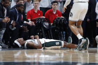 Michigan State's Cassius Winston, bottom, reacts in front of the Ohio State bench after being fouled on a three-point basket during the first half of an NCAA college basketball game, Sunday, March 8, 2020, in East Lansing, Mich. (AP Photo/Al Goldis)