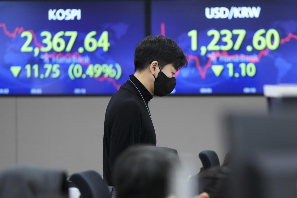 A currency trader works near screens showing the Korea Composite Stock Price Index (KOSPI), left, and the foreign exchange rate between the U.S. dollar and South Korean won at the foreign exchange dealing room of the KEB Hana Bank headquarters in Seoul, South Korea, Wednesday, Jan. 18, 2023. Asian shares were mostly lower Wednesday after Japan’s central bank kept its lax monetary policy unchanged, contrary to speculation it would yield to pressure to tighten credit to counter rising inflation. (AP Photo/Ahn Young-joon)