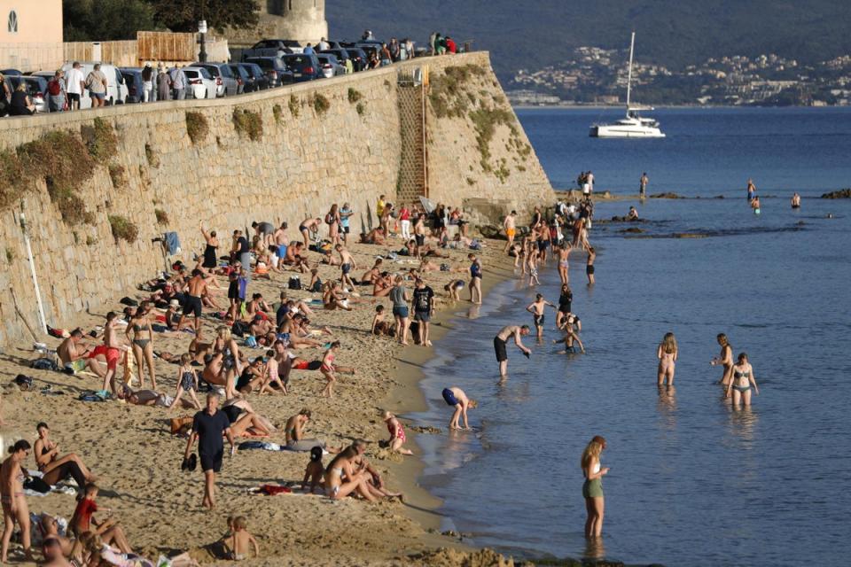 Local residents and tourists enjoy the warm weather at the Saint Francois beach in Ajaccio on the French Mediterranean island of Corsica on October 19, 2022. (AFP via Getty Images)