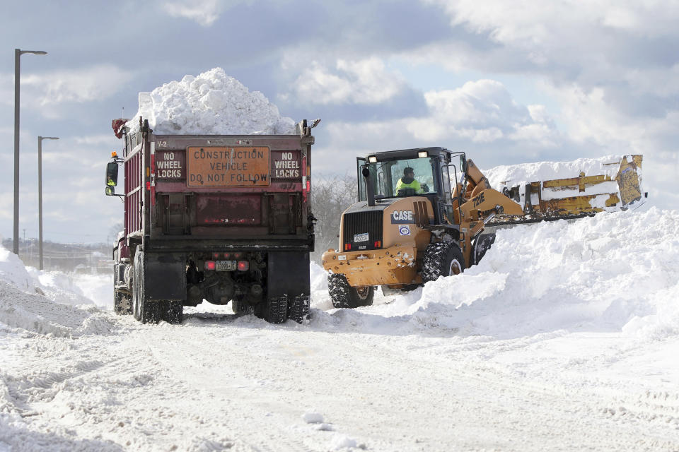 Crews truck snow in to dump in the parking lot of Erie Community College in Orchard Park in Erie County, N.Y., Sunday, Nov. 20, 2022. (Mark Mulville/The Buffalo News via AP)