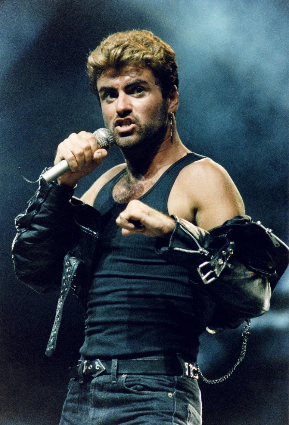 george michael holding a microphone during a performance