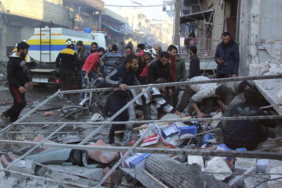 This photo released by the opposition Syrian Civil Defense rescue group, also known as White Helmets, which has been authenticated based on its contents and other AP reporting, shows Civil Defense workers and people searching for victims under the rubble of a destroyed building that was hit by airstrikes in the village of Balyoun, in Idlib province, Syria, Saturday, Dec. 7, 2019. Airstrikes on areas in the last major rebel stronghold in northwest Syria on Saturday killed at least 18 people, including women and children, and wounded others as a three-month truce crumbles, opposition activists said. (Syrian Civil Defense White Helmets via AP)