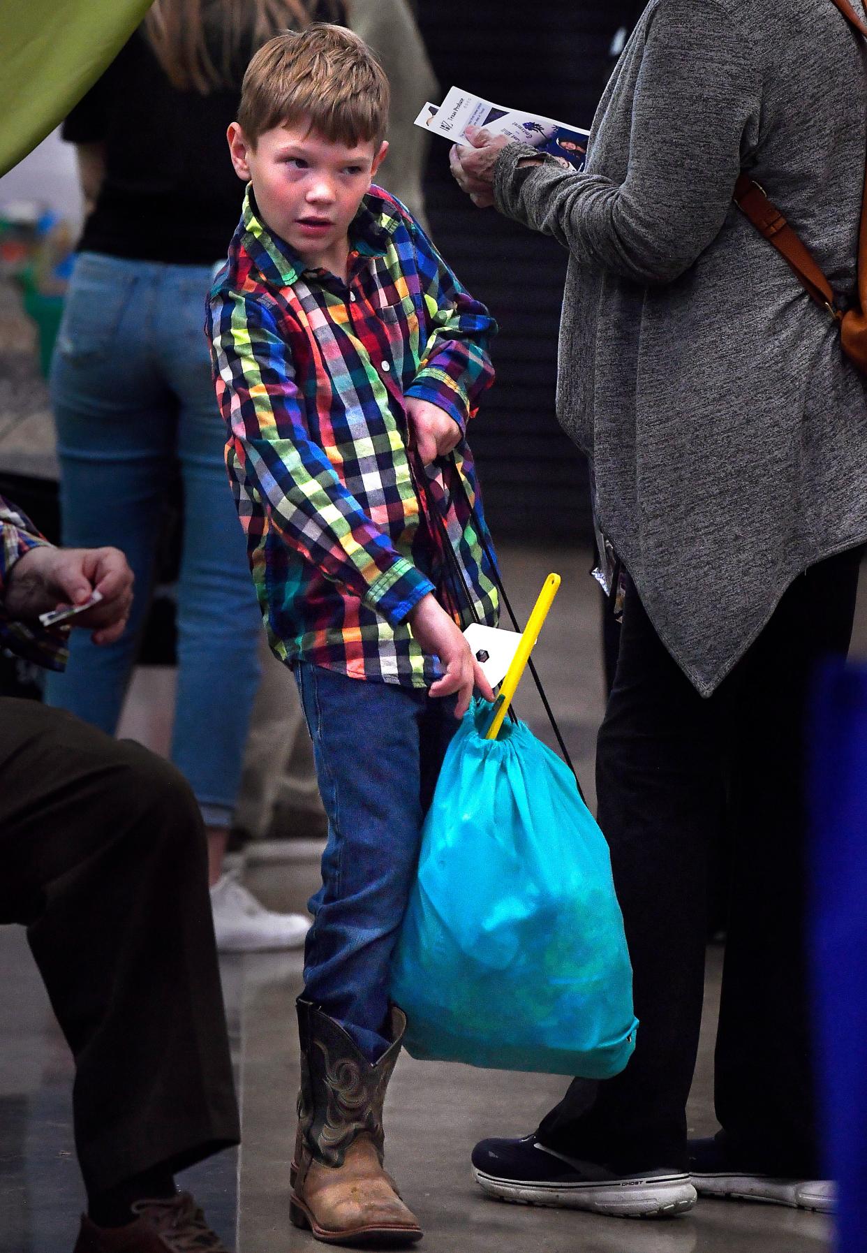Iam Smith, 9, hefts a bag of giveaway swag as visitors crowd Business Expo Wednesday at the Abilene Convention Center.