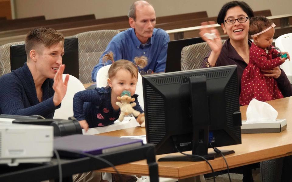 Dr. Erin Meyer and her wife Dr. Sandra Medinilla wave to family and friends that video chatted during the adoption ceremony of their fourth child 6-month-old Sydney.