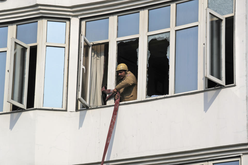 A fire official rolls up a hosepipe after extinguishing an early morning fire at the Arpit Palace Hotel in the Karol Bagh neighborhood of New Delhi, India, Tuesday, Feb.12, 2019. More than a dozen people were killed. (AP Photo/Manish Swarup)