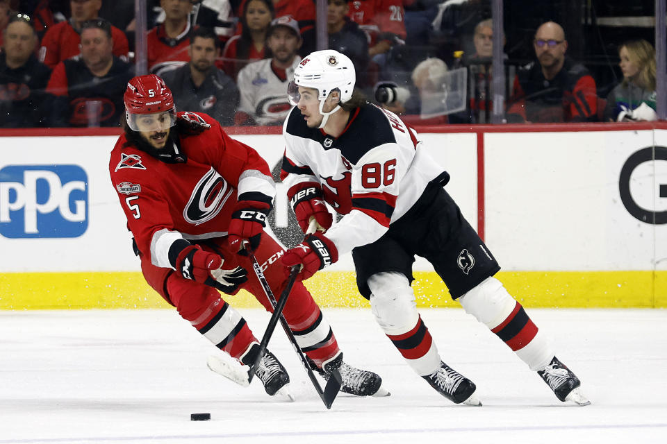 New Jersey Devils' Jack Hughes (86) tries to protect the puck from Carolina Hurricanes' Jalen Chatfield (5) during the second period of Game 2 of an NHL hockey Stanley Cup second-round playoff series in Raleigh, N.C., Friday, May 5, 2023. (AP Photo/Karl B DeBlaker)