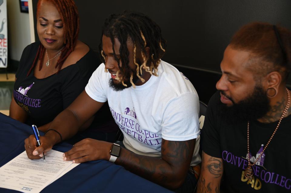 Davidson-Davie Community College point guard Uzziah Dawkins signs his letter of intent to play basketball at Converence College as his parents look on.