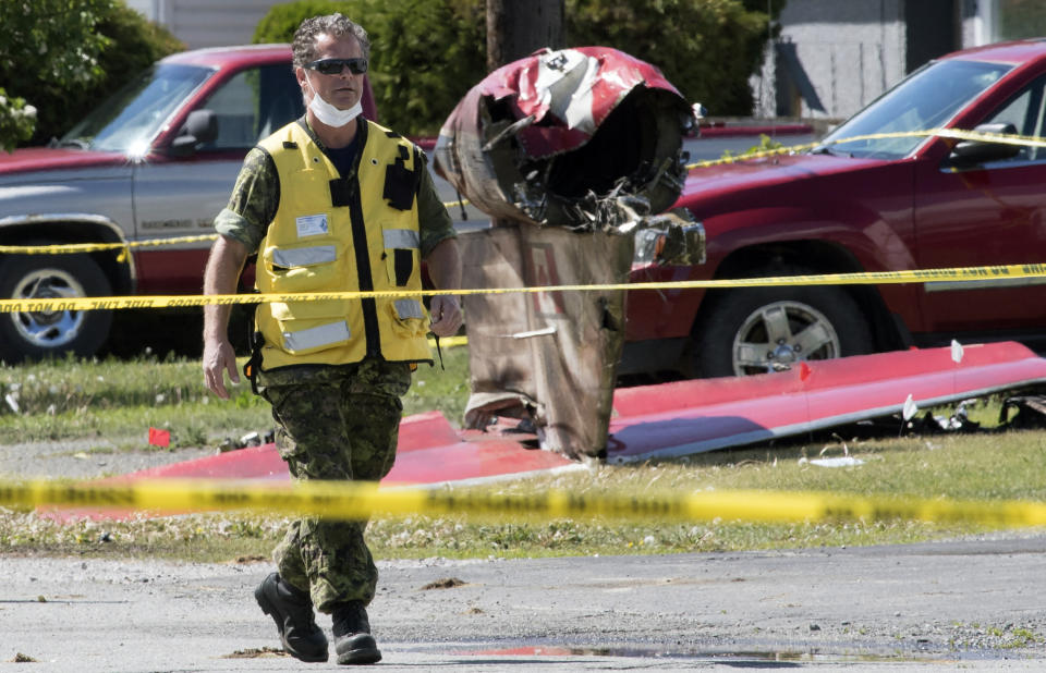 A member of the Canadian Forces walks past the tail section of a crashed Snowbird jet in Kamloops, British Columbia, Monday, May 18, 2020. Capt. Jennifer Casey died Sunday after the Snowbirds jet she was in crashed shortly after takeoff. The pilot of the aircraft is in hospital with serious injuries. (Jonathan Hayward/The Canadian Press via AP)