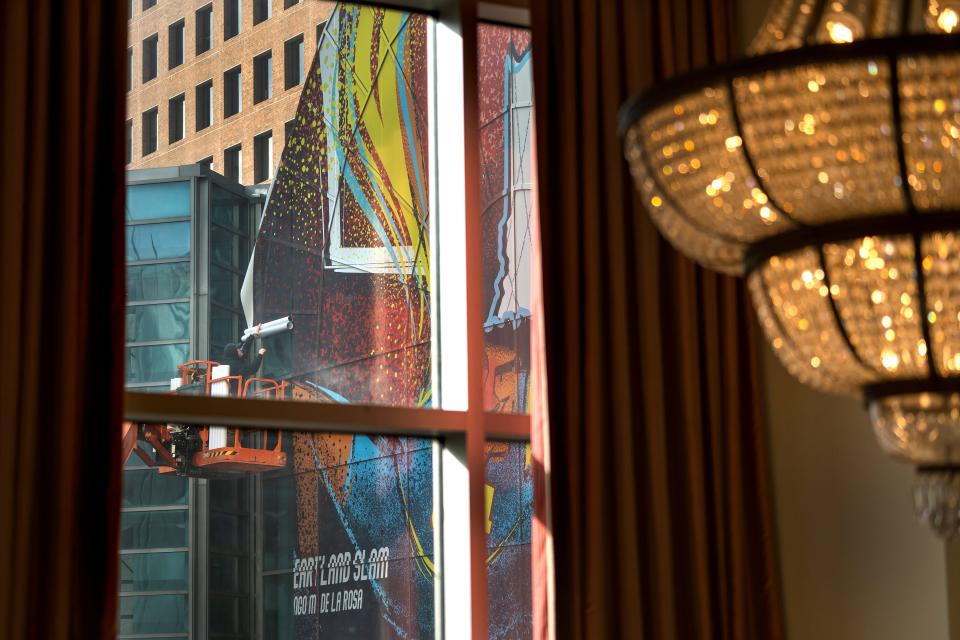 Signs of the upcoming NBA All-Star Game are seen in downtown Indianapolis Thursday, Feb. 1, 2024. Seen from a second floor hallway in the Conrad Indianapolis, a workman pieces together a mural on the Indianapolis Artsgarden.