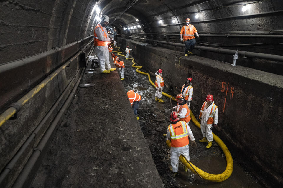 Amtrak workers perform tunnel repairs to a partially flooded train track bed, Saturday, March 20, 2021, in Weehawken, N.J. With a new rail tunnel into New York years away at best, Amtrak is embarking on an aggressive and expensive program to fix a 110-year-old tunnel in the interim. (AP Photo/John Minchillo)